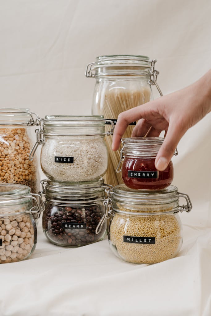A neat arrangement of labeled glass jars containing beans, rice, and more, in a pantry setting.